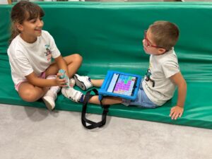 Hermana de niño con daño cerebral, durante una sesión de logopedia de su hermano para aprender a utilizar el comunicador